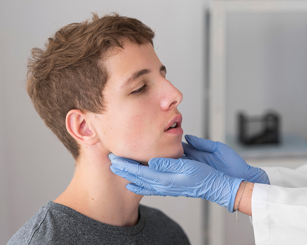 Healthcare professional palpating teen’s Chin for assessment.